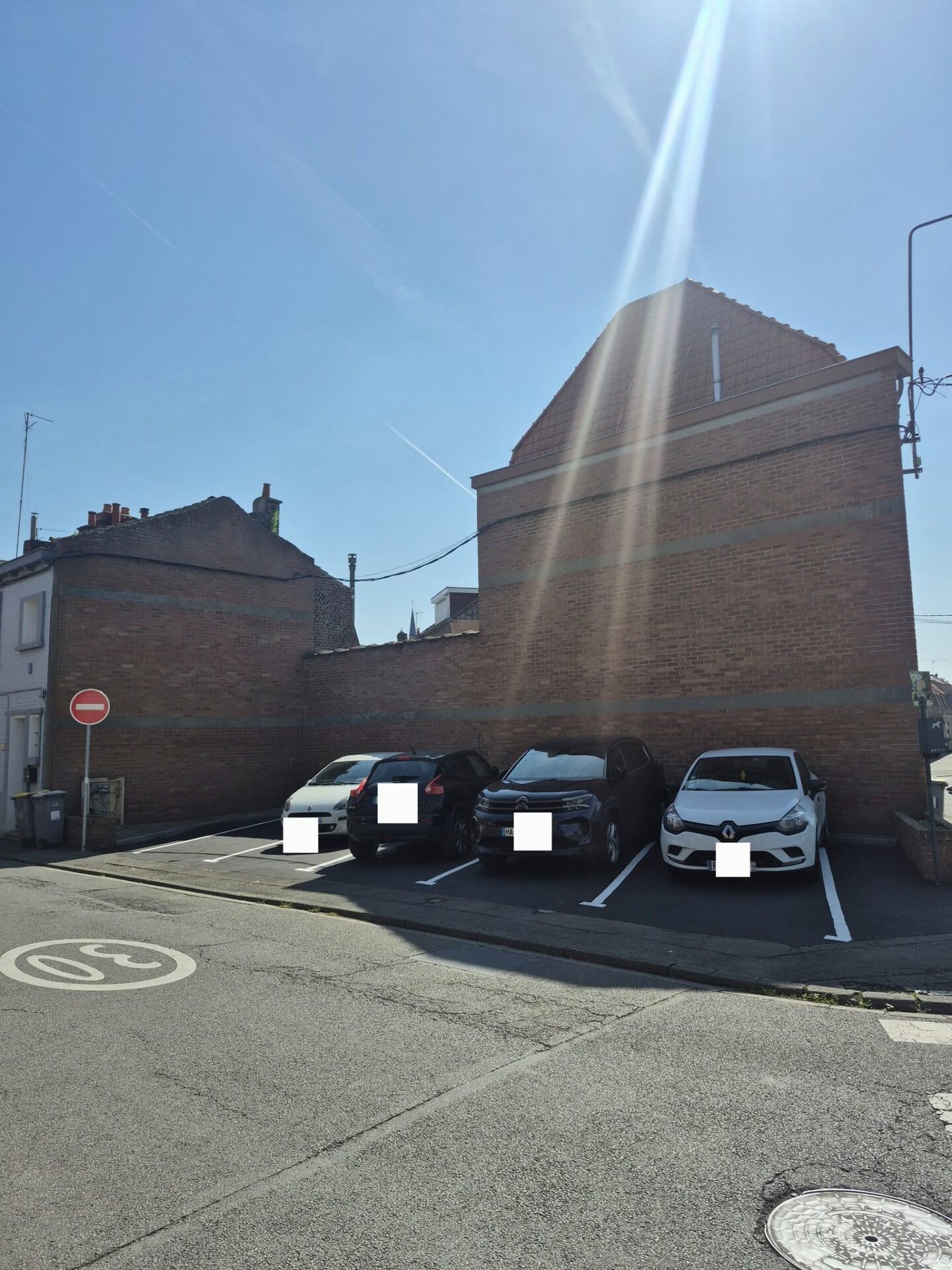 Après : quatre voitures stationnées sur les nouvelles places bétonnées contre le mur en brique
